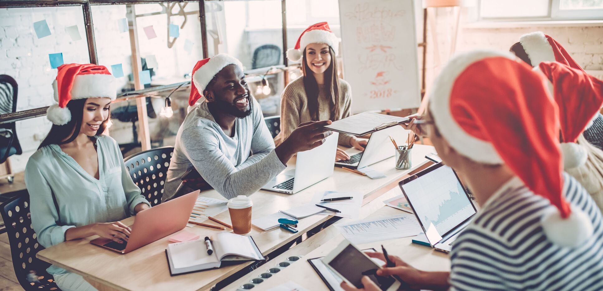 Mitarbeiter arbeiten während der Weihnachtszeit mit Weihnachtsmütze bekleidet im gemeinsamen Büro.