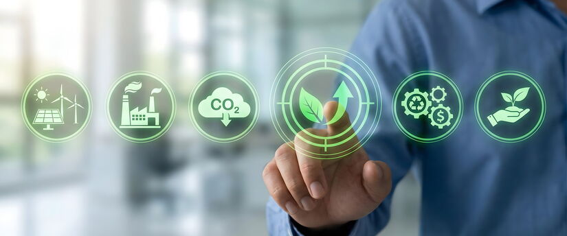 Person tippt vor unscharfem Büro-Hintergrund auf eingeblendete, transparente Symbole für CO₂-Reduktion, erneuerbare Energien und Klimaschutz.
