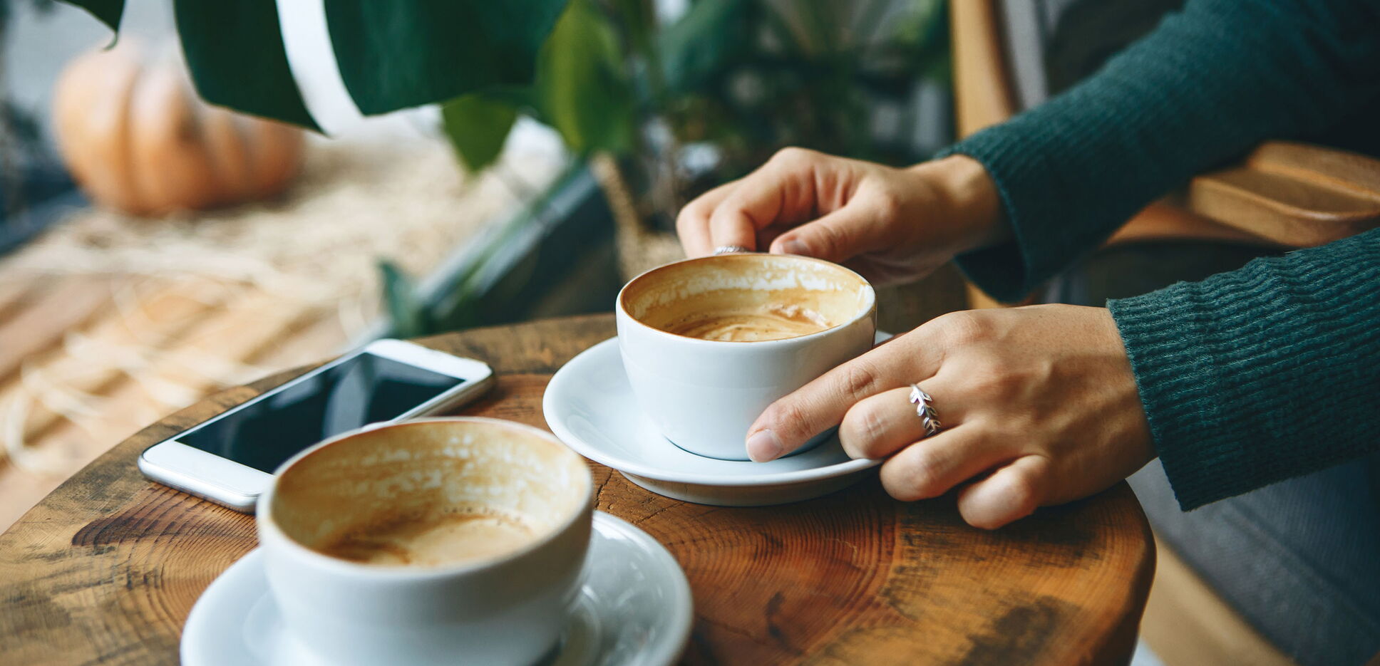 Bewerberin mit Kaffee im Bewerber-Café, Handy auf dem Tisch, symbolisiert Offenheit für Karrieregespräche bei der peepz GmbH.