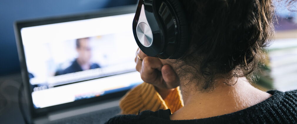 Frau mit Kopfhörern arbeitet auf dem Laptop