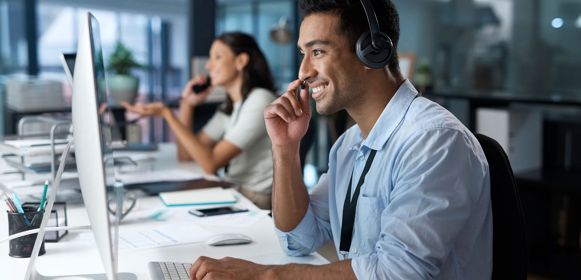 Aufnahme eines Mannes, der ein Headset und einen Computer in einem modernen Büro benutzt.