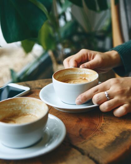 Bewerberin mit Kaffee im Bewerber-Café, Handy auf dem Tisch, symbolisiert Offenheit für Karrieregespräche bei der peepz GmbH.