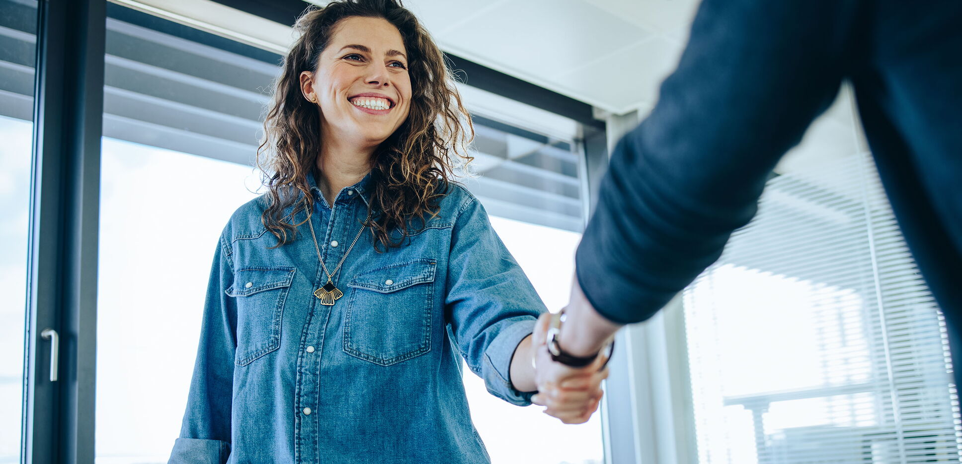 Recruitment Manager schüttelt Hand einer lächelnden Bewerberin