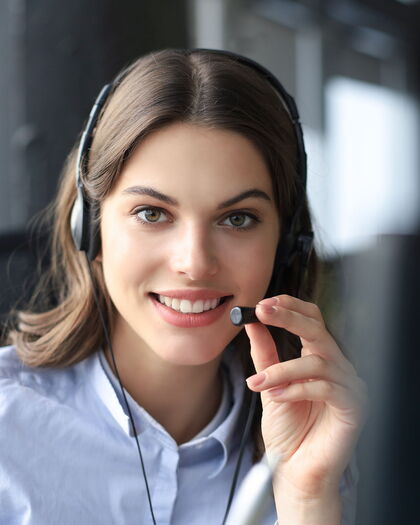 Virtuelle Assistenz mit Headset schaut lächelnd in die Kamera.