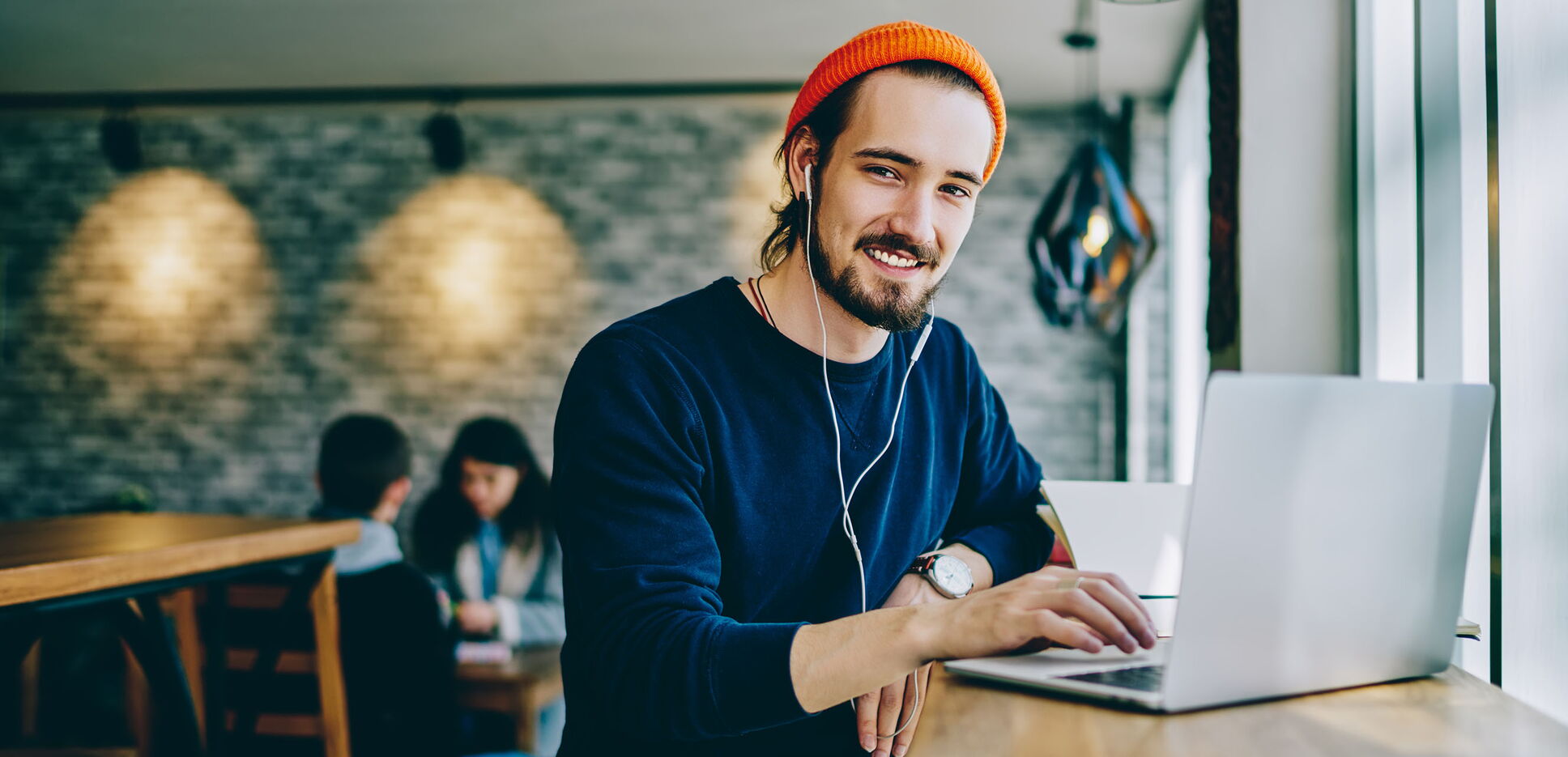 Junger Mann, der am Tisch mit einem Laptop arbeitet.