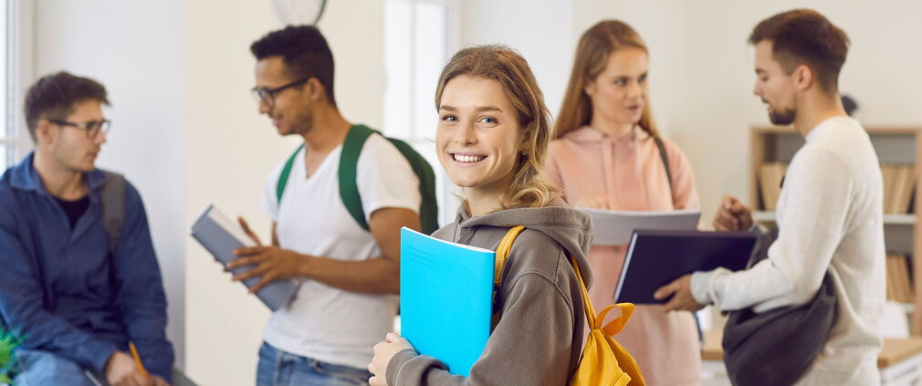 Studentin mit fröhlichem Gesichtsausdruck im Seminarraum.