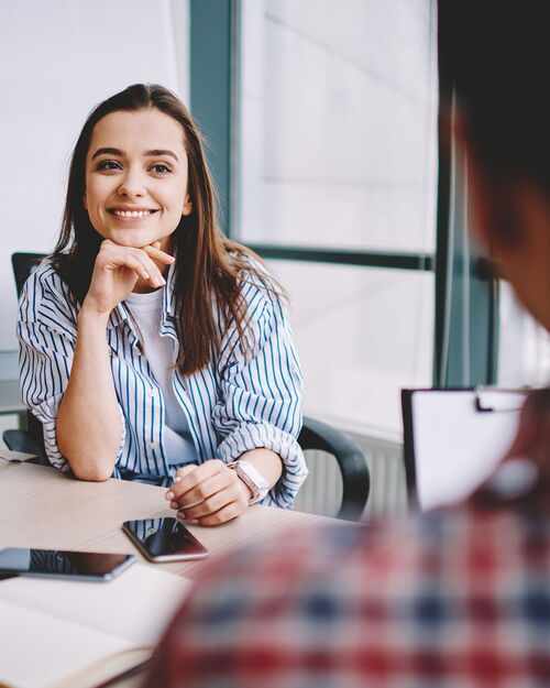 Frau, die einem männlichen Kollegen während eines positiven Gesprächs im Büro zuhört.