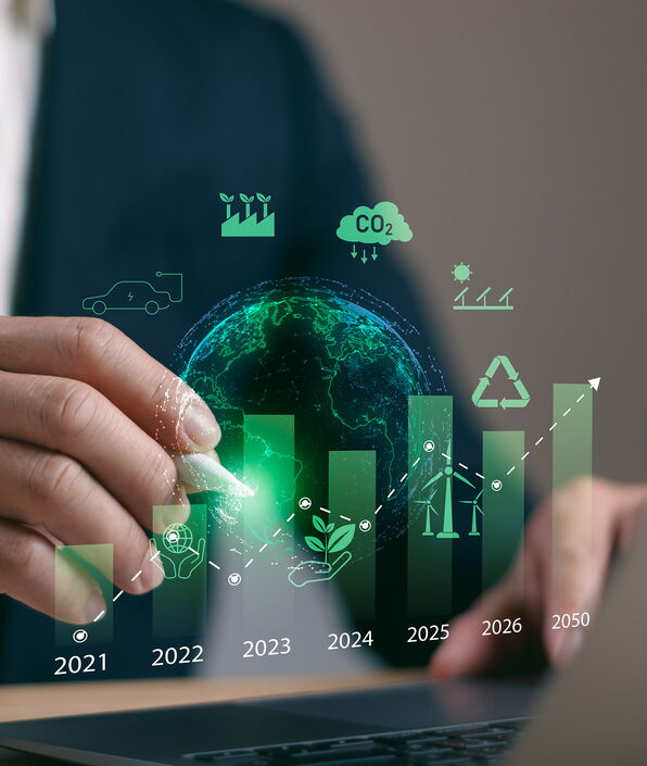Person zeichnet ein eingeblendetes Balkendiagramm mit grüner Wachstumskurve von 2021 bis 2050 – flankiert von Symbolen für CO₂-Reduktion, E-Mobilität, Recycling und erneuerbare Energien.