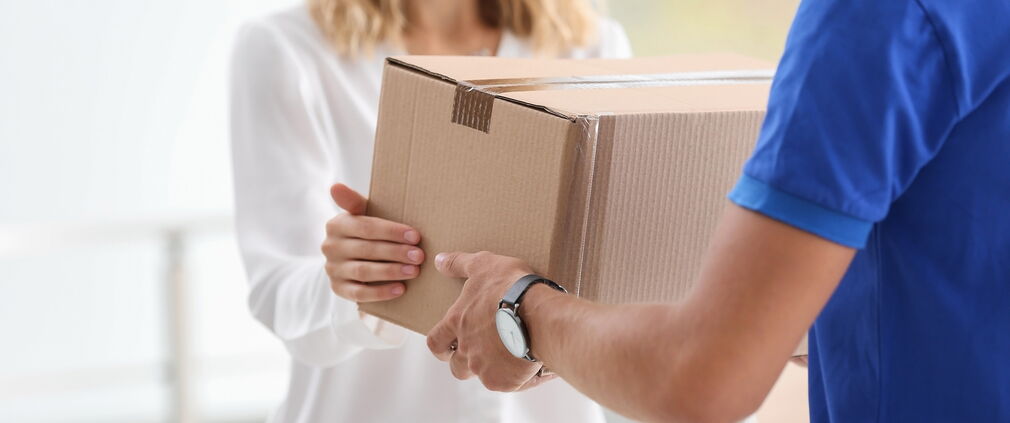 Junge Frau, die ein Paket von einem Kurier in einem Haus erhält