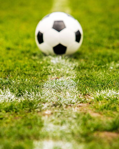 Fußball platziert auf der weißen Markierungslinie des Stadionrasens.