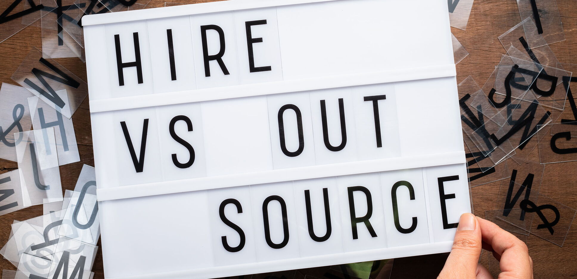Schiebeleuchtungsschild mit dem Text: Hire VS Outsource