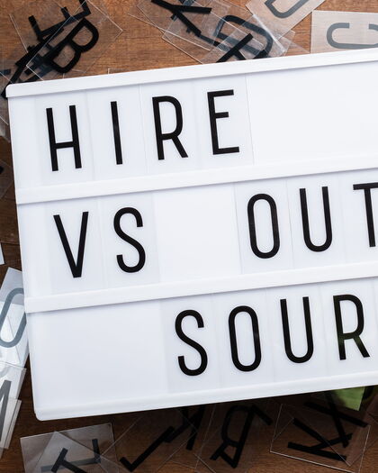 Schiebeleuchtungsschild mit dem Text: Hire VS Outsource